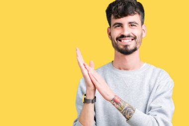 Genç yakışıklı adam giyen kazak izole üzerinde arka plan Clapping ve mutlu ve neşeli, gururlu gülümseyen birlikte eller alkış