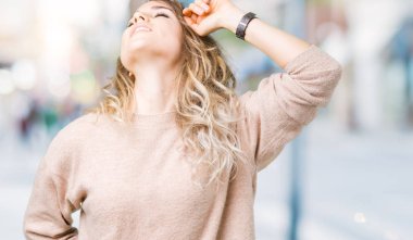 Sweatershirt üzerinde giyen genç güzel sarışın kadın arka plan geri uzanan izole, yorgun ve rahat, Uykulu ve erken sabah esneme