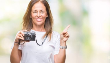 Orta yaş İspanyol kadın izole arka tarafına el ve parmak ile işaret çok mutlu üzerinde Vintage Fotoğraf kamera ile fotoğraf çekmek