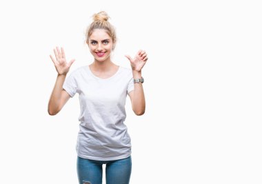 Gösterilen ve parmakları ile işaret izole arka plan üzerinde beyaz t-shirt giyen genç güzel sarışın kadın kendinden emin ve mutlu gülümseyerek süre 6 numara.