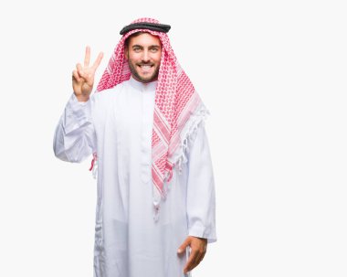 Keffiyeh üzerinde giyen genç yakışıklı adam arka plan gösteren izole ve parmakları ile işaret kendinden emin ve mutlu gülümseyerek ise ikinci.