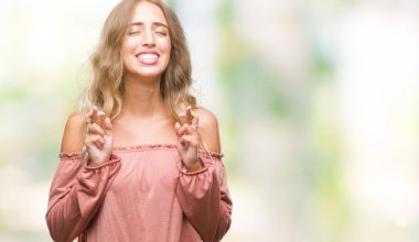 Güzel sarışın genç kadın geçiş parmakları umut ve gözleri kapalı ile gülümseyen izole arka plan üzerinde. Şans ve batıl kavramı.