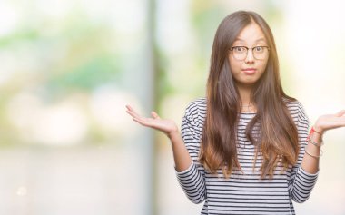 Üzerinde gözlük takan Genç Asyalı kadın arka plan clueless ve şaşkın bir ifadeyle kollar ve eller kaldırdı izole. Şüphe kavramı.