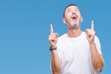 Orta yaş ağarmış komuta sizde izole arka plan üzerinde beyaz t-shirt giyen hayrete ve yukarıya bakıyor ve parmakları ile işaret ve silah kaldırdı şaşırttı.