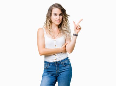 Yüzünde kocaman bir gülümseme ile izole arka plan üzerinde genç güzel sarışın kadın kameraya bakarak yan el ve parmak ile işaret.
