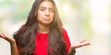 Genç güzel Arap kadın izole arka plan clueless ve şaşkın bir ifadeyle kollar ve eller kaldırdı. Şüphe kavramı.