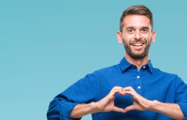 Yakışıklı delikanlı aşık kalp simgesi ve elleriyle şekil gösteren gülümseyen izole arka plan üzerinde. Romantik kavramı.