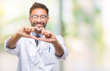 Aşık kalp simgesi ve elleriyle şekil gösteren gülümseyen izole arka plan üzerinde beyaz önlük giyiyor yetişkin Latin asıllı bilim adamı ya da doktor adam. Romantik kavramı.