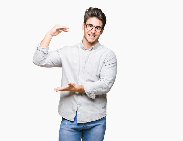 眼鏡をかけてメジャー シンボル兆し大きな 大きなサイズの手で身振りで示す分離の背景の上の若いハンサムな男 カメラを見て笑っています 測定概念 — ストック写真