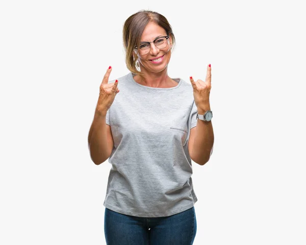 中年的高级西班牙妇女戴着眼镜在孤立的背景大喊与疯狂的表情做岩石符号与手 音乐明星 沉重的概念 — 图库照片