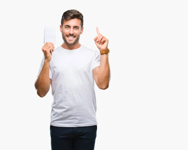 Joven Hombre Guapo Sosteniendo Cuaderno Sobre Fondo Aislado Sorprendido Con —  Fotos de Stock