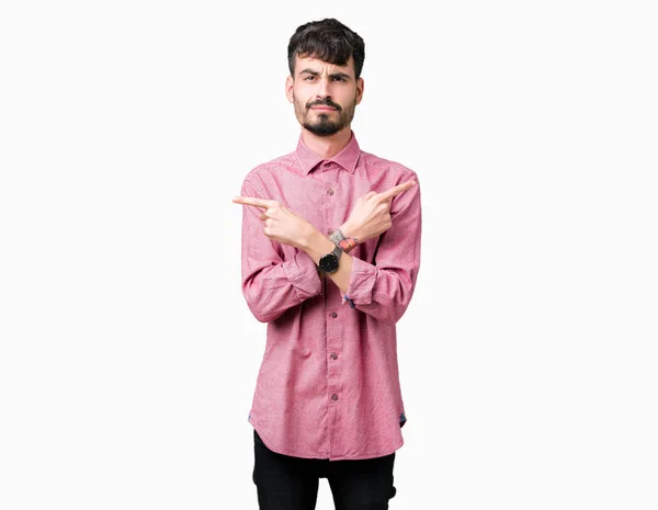 年轻英俊的男人穿着粉红色的衬衫在孤立的背景指向两侧的手指 不同的方向不同意 — 图库照片