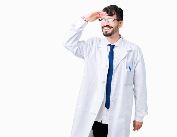 Young professional scientist man wearing white coat over isolated background very happy and smiling looking far away with hand over head. Searching concept.