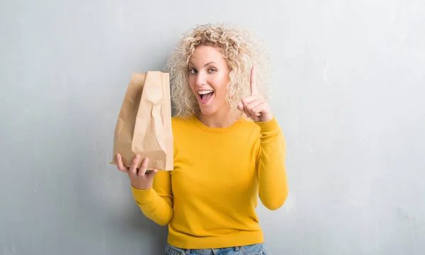 Unga Blonda Kvinnan Över Grunge Grå Bakgrund Håller Lunch Papperspåse — Stockfoto