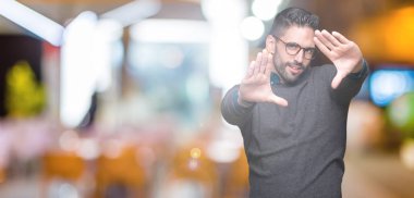 Genç yakışıklı adam gözlük izole üzerinde çerçeve kullanarak el avuç içi ve parmaklar, kamera perspektif yapıyor gülen arka plan