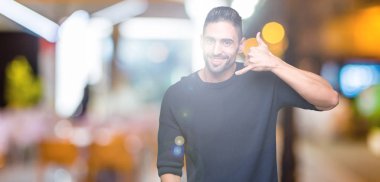 Kazak yapıyorsun gülümseyen izole arka plan üzerinde giyen genç yakışıklı adam telefon hareketi ile el ve parmak telefonda konuşuyor gibi. Kavramları iletişim.