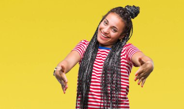 Genç saç Afro-Amerikan kız sarılmak için kollarını açarak gülümseyerek kameraya bakarak izole arka plan üzerinde örgülü. Neşeli ifade kucaklayan mutluluk.