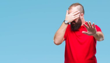 Üzerinde kırmızı gömlek giyen genç beyaz hipster adam izole elleriyle gözlerini kapsayan arka plan ve stop jest ile acı ve korku ifadesi. Utandım ve negatif kavramı.
