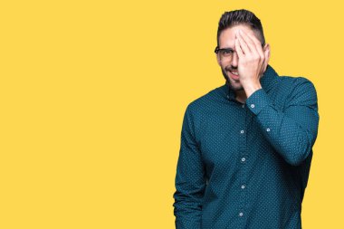 El yüz ve sürpriz duygu kendinden emin gülümseme ile tek gözüyle kapsayan izole arka plan üzerinde gözlük takan genç yakışıklı iş adamı.