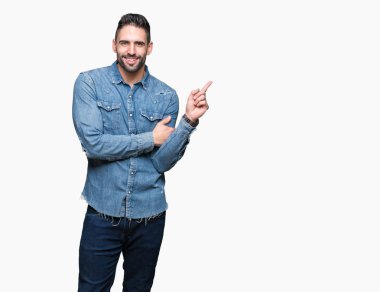 Kameraya bakarak yan el ve parmak ile işaret eden genç yakışıklı adam yüzünde kocaman bir gülümseme ile izole arka plan üzerinde.