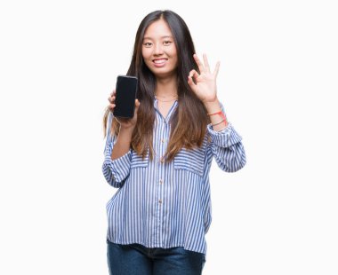 Genç Asyalı kadın gösteren boş ekran smartphone üzerinde parmak, mükemmel sembolü ile ok işareti yapıyor izole arka plan