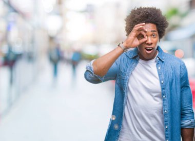 Sürpriz yüz, göz parmaklarının arasından seyir ile ok jest yapıyor izole arka plan üzerinde Afro Amerikalı adam şok. İmansız ifade.