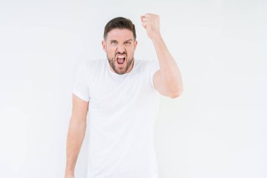 Öfkeli ve sinirli sinirli ve öfke ile bağırarak süre öfkeli yumruk yükselterek izole arka plan üzerinde rahat beyaz t-shirt giyen genç yakışıklı adam. Öfke ve agresif kavramı.