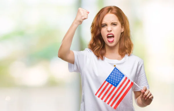 年轻美丽的妇女持有美国国旗在孤立的背景懊恼和沮丧的呼喊与愤怒 疯狂和叫喊与举手 愤怒的概念 — 图库照片