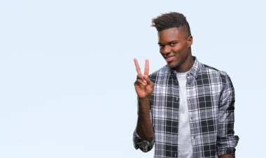 Afrikalı-Amerikalı genç mutlu yüz zafer işareti yaparken kameraya göz kırpıyor ile gülümseyen izole arka plan üzerinde. İki numaralı.