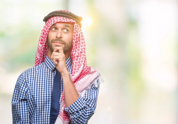 あごを考えて質問 物思いにふける式の手で隔離された背景にクーフィーヤを着た若いハンサムなアラビアン ビジネス男 思いやりのある顔をして笑っています 疑いのコンセプト — ストック写真