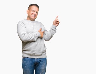 Kameraya bakarak yan el ve parmak ile işaret yüzünde kocaman bir gülümseme ile izole arka plan üzerinde spor kazak giyen orta yaş Arap adam.