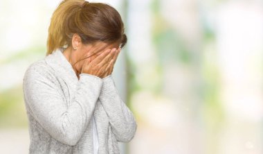 Yüzünü elleriyle ağlayarak süre kapsayan üzgün ifade ile izole arka plan üzerinde kış kazak giyen güzel orta yaş yetişkin kadın. Depresyon kavramı.