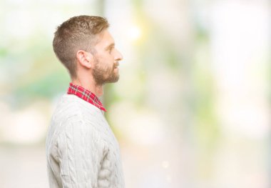 Genç yakışıklı adam giyen kış kazak izole arka tarafına, seyir üzerinde dinlenmek doğal yüz emin gülümseme ile pozuyla profili.