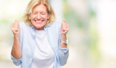 Orta yaş sarışın kadın izole arka kolları olan başarı için heyecan üzerinde zafer kutluyor gülümseyen kaldırdı. Kazanan kavramı.