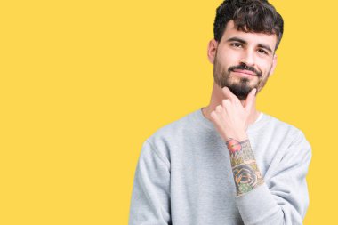 Emin çapraz kollar ve çeneme kaldırdı el ile gülümseme ile kameraya bakarak izole arka plan üzerinde kazak giyen genç yakışıklı adam. Pozitif düşünce.