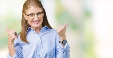 El ile pozitif jest yapıyor izole arka plan başarı işareti üzerinde gözlük güzel orta yaş olgun iş kadını başparmak gülümseyen ve mutlu. Neşeli bir ifadeyle, kazanan jest kameraya bakıyor.