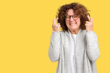 Ceket ve gözlük geçiş parmakları umut ve gözler gülümseyen izole arka plan üzerinde giyen güzel orta ager üst düzey kadın kapalı. Şans ve batıl kavramı.