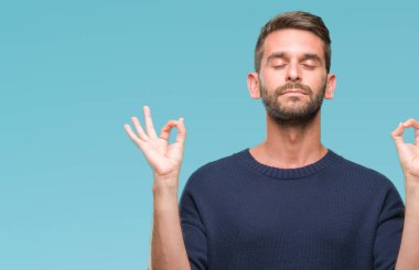 Genç yakışıklı adam giyen kış kazak izole arka plan üzerinde dinlenmek ve gülümseyen gözlerle parmak ile meditasyon jest yapıyor kapalı. Yoga kavramı.