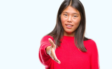 Üzerinde kış kazak giyen genç Asyalı kadın arka plan dostu sunan karşılıklı tebrik ve davet edici gülümseyen izole. Başarılı iş.