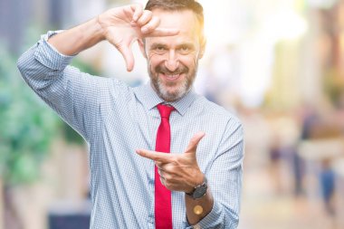 Orta yaş ağarmış üst düzey iş adamı elle yapma çerçeve ve parmakları ile mutlu yüz gülümseyen izole arka plan üzerinde kırmızı kravat takıyor. Yaratıcılık ve Fotoğrafçılık kavramı.