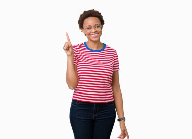 Güzel genç Afrikalı-Amerikalı kadın ve kendinden emin ve mutlu gülümseyerek süre parmak numaralı yukarıyı gösteren izole arka plan üzerinde gözlük.
