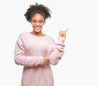 Kameraya bakarak yan el ve parmak ile işaret yüzünde kocaman bir gülümseme ile izole arka plan üzerinde gözlük takan genç afro Amerikalı kadın.