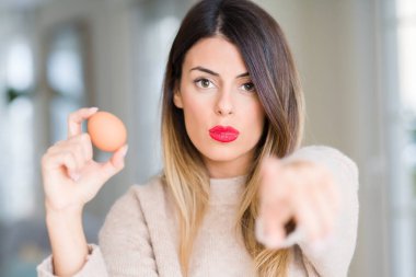 Genç güzel kadın tutarak taze yumurta evde işareti, pozitif ve kendinden emin bir jest ön el kamera ve size, parmak ile işaret