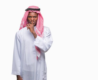 Dudaklarında parmak ile sessiz olmanı izole arka plan üzerinde geleneksel keffiyeh giyen genç Arapça Afrika adam. Sessizlik ve gizli kavramı.