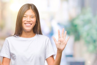 Genç Asyalı kadın gösterilen ve parmakları ile işaret izole arka plan üzerinde kendinden emin ve mutlu gülümseyerek süre 6 numara.