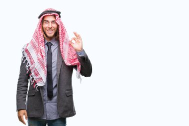Genç yakışıklı Arap adam uzun saçlı keffiyeh izole arka plan el ve parmaklar ok işaretiyle yapıyor olumlu gülümseyen üzerinde giyiyor. Başarılı ifade.