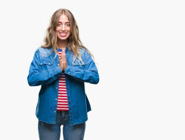 Birlikte emin gülümseyen bağışlanmak ellerle dua izole arka plan üzerinde sarışın güzel genç kadın.