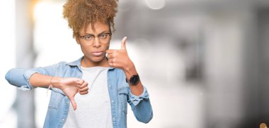 Güzel genç Afro-Amerikan kadın yukarı ve aşağı izole arka plan yapmaya başparmak üzerinde gözlük, anlaşmazlık ve anlaşma ifade. Deli çatışma