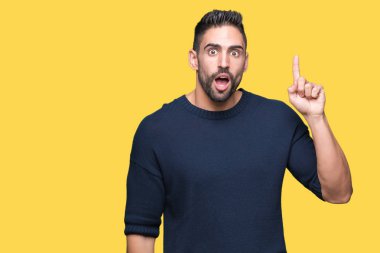 Genç yakışıklı adam başarılı fikirle izole arka plan işaret parmağı üzerinde kazak giyiyor. Çıktıktan ve mutlu. Bir numara.