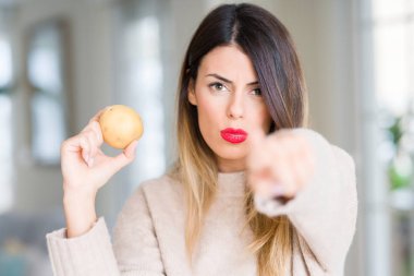 Genç güzel kadın tutarak taze patates evde işareti, pozitif ve kendinden emin bir jest ön el kamera ve size, parmak ile işaret